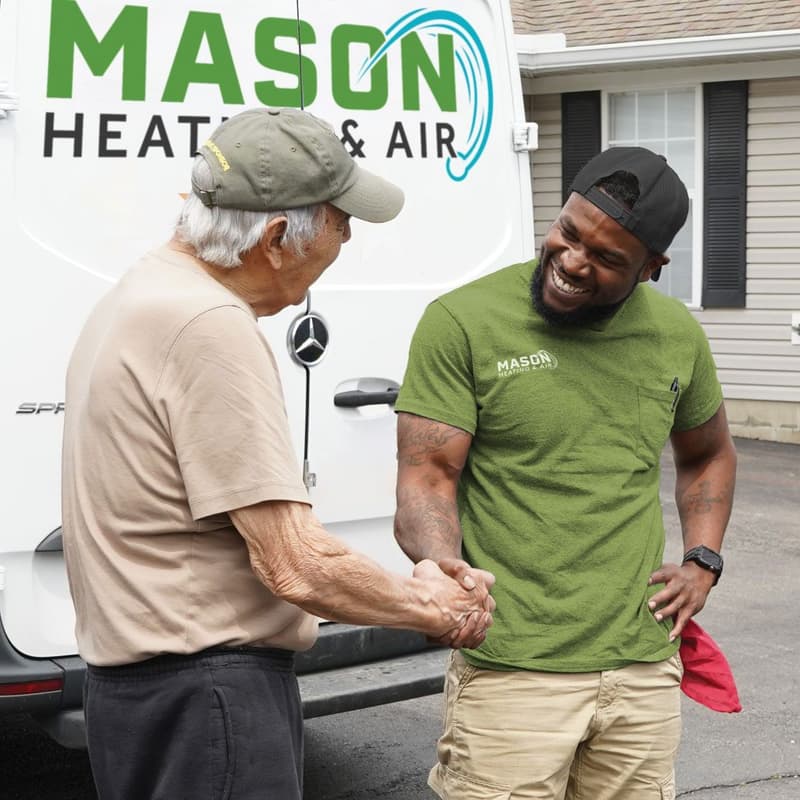 Technician shaking hands with customer beside company van
